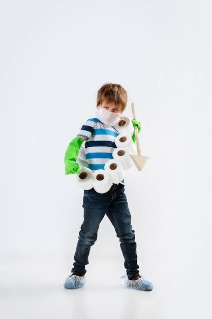 Little caucasian boy as a warrior in fight with coronavirus pandemic, with a shield, a spear and a toilet paper bandoleer, attacking