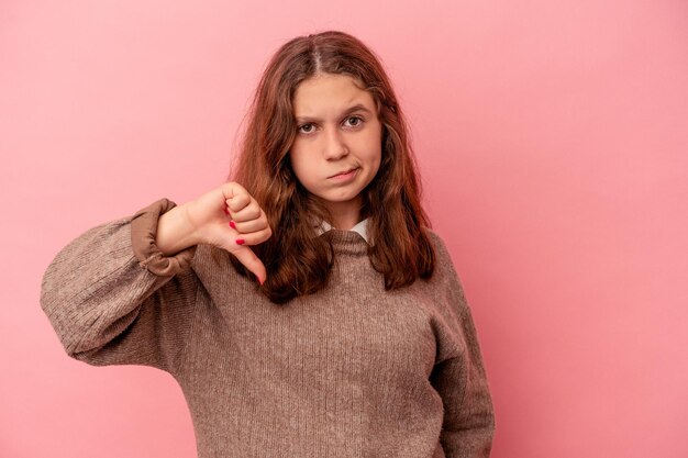 Little caucasian girl isolated on pink background showing thumb down, disappointment concept.
