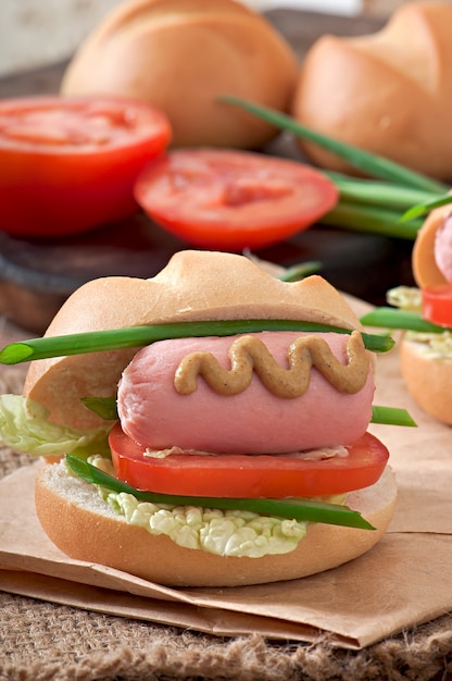 Free photo little cheerful hot dog with sausage and tomato