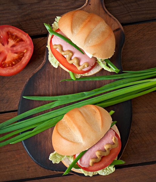 Little cheerful hot dog with sausage and tomato