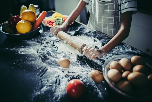 반죽을 스트레칭 롤링 핀을 사용하여 작은 요리사. 요리 개념.