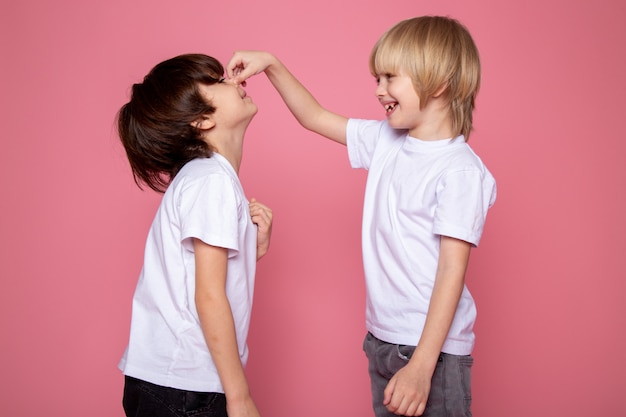 Free photo little child boys adorable sweet playing with each other on pink wall