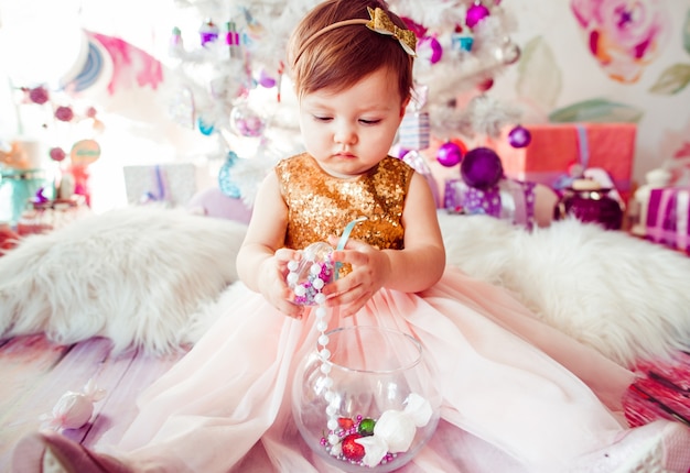 Little child in golden dress plays on the floor 