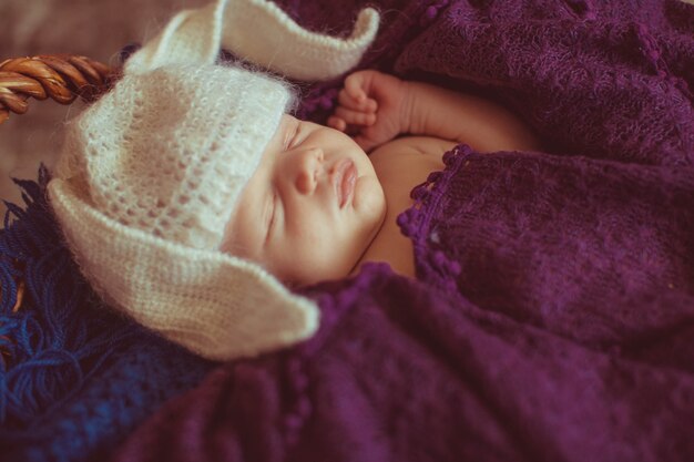 Little child in hat like rabbit ears sleeps under the scarf