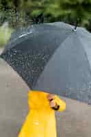 Free photo little child holding a big black umbrella