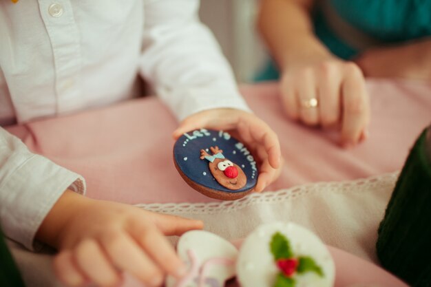 Little child holds cookie with lettering 'Let it snow'