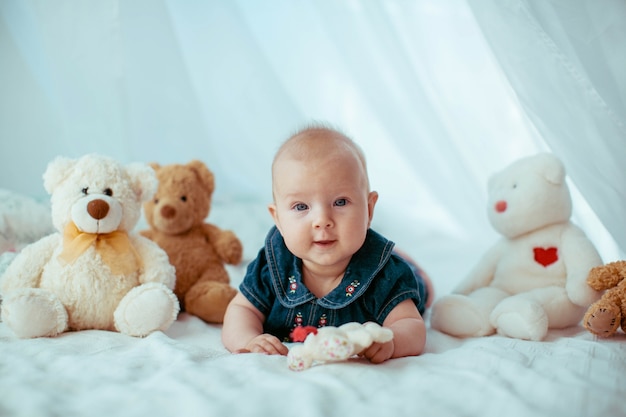Little child lies among toy bears on bed