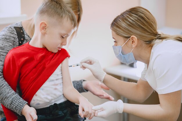 小さな子供の医療訪問。腕に子供注射を与える医師。