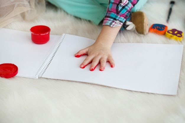 Little child raises her palm painted in red