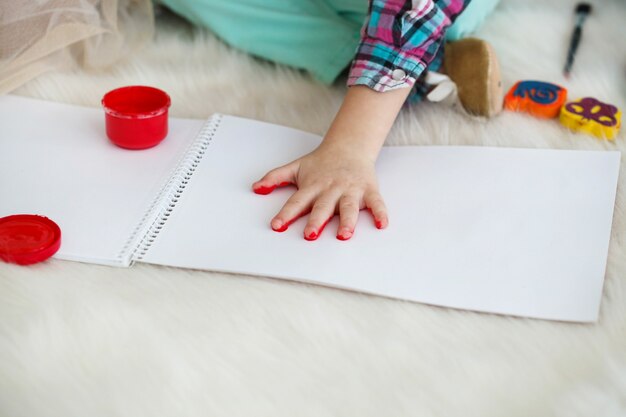 작은 아이가 그녀의 손바닥을 빨간색으로 그린다