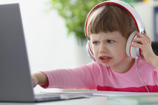 Little child not satisfied with something point with finger on laptop screen