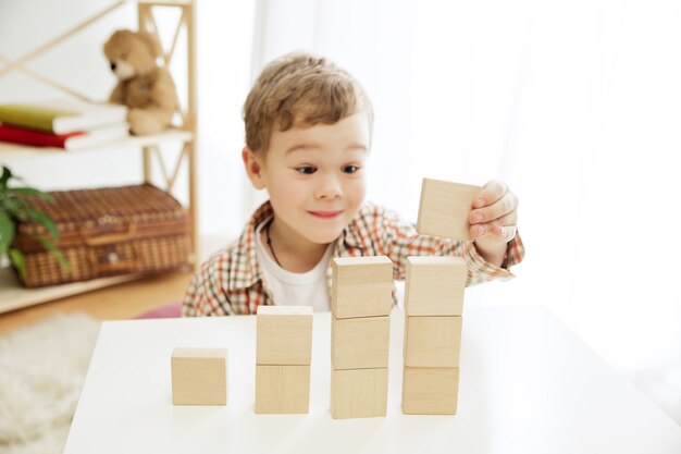 Little child sitting on the floor pretty boy palying with wooden cubes at home