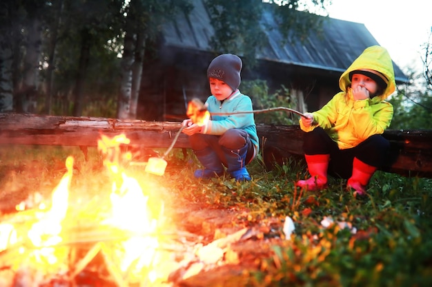 Маленькие дети жарят зефир ночью у костра. летний лагерь