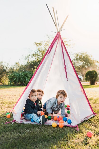 Little children sitting in tepee and playing with balls