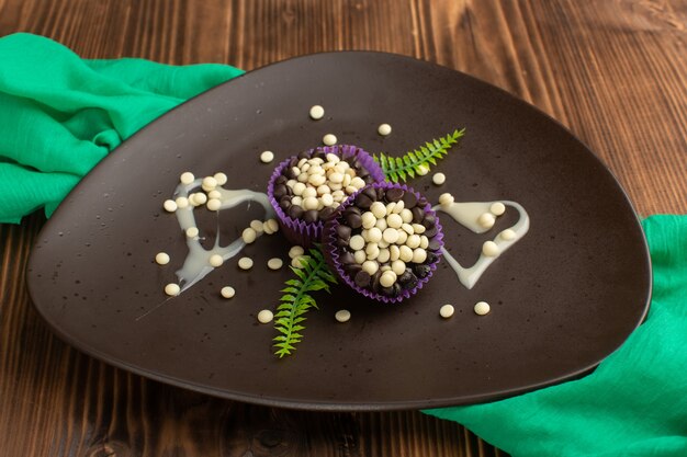 little chocolate brownies with chocolate chips inside dark plate on wood