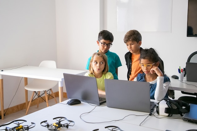 Little classmates doing group task, using laptops and studying at computer school