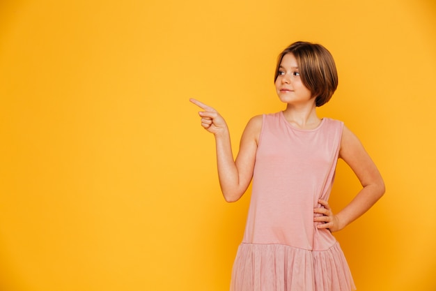 Little confident girl pointing at copy space isolated