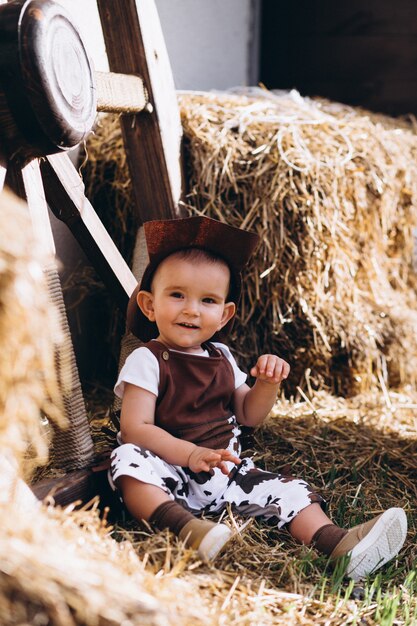 Free photo little cowboy sitting on hay