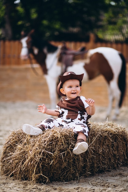 Little cowboy sitting on hay