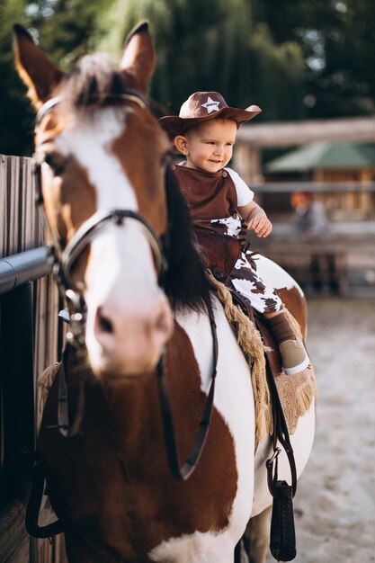 Маленький ковбой, сидящий на лошади