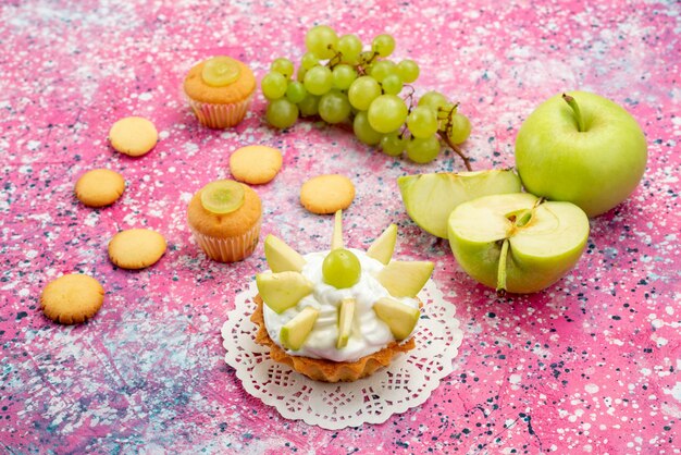 little creamy cake with sliced fruits cookies grapes on colored desk, cake sweet bake