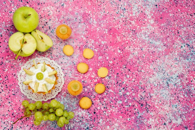 little creamy cake with sliced fruits cookies grapes on colored desk, cake sweet sugar bake color