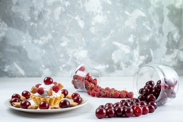 little creamy cake with sour fresh cherries and raspberries on light, fresh fruit berry cake sweet