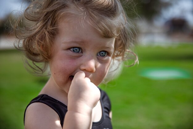 Маленькая фигурная девочка летом на открытом воздухе крупным планом на размытом фоне
