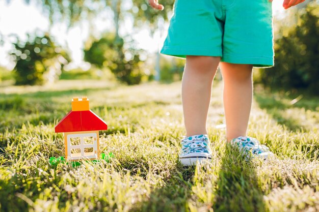 Little cute boy and his house in summer garden.