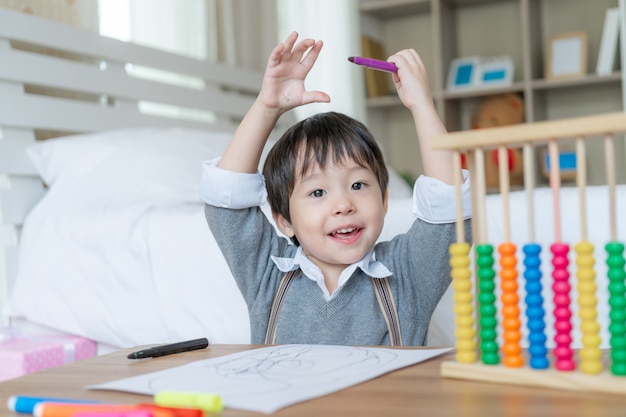 彼が幸せに絵を描き終えると誇りに思っているかわいい男の子は、彼の頭と笑顔で両手を上げた