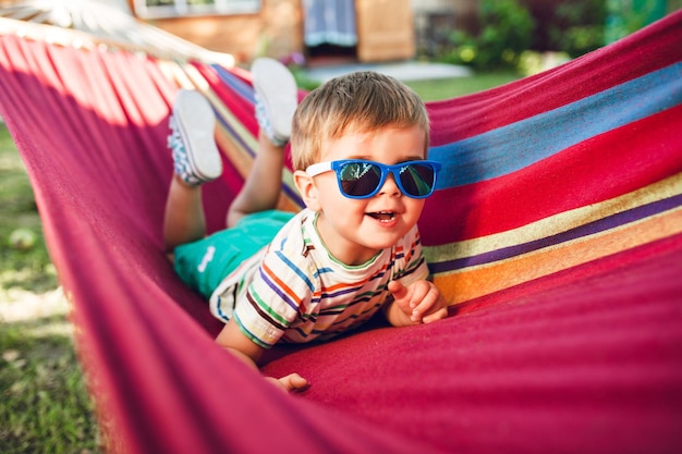 Little cute boy resting on bright hammock and having fun. in his sunglasses.