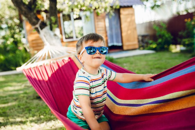 Little cute boy sitting on bright hammock and having fun.