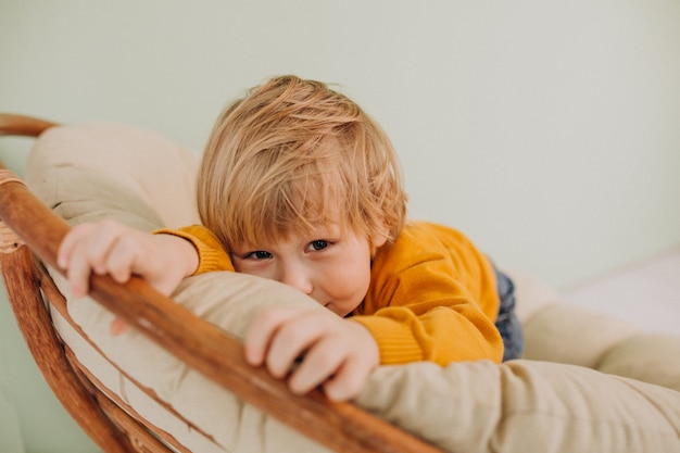 Free photo little cute boy sitting in a chair