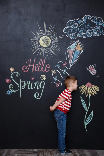 Little cute boy smelling flower on the chalk black board