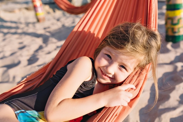 Piccola ragazza carina vestita in costume da bagno nero sulla spiaggia