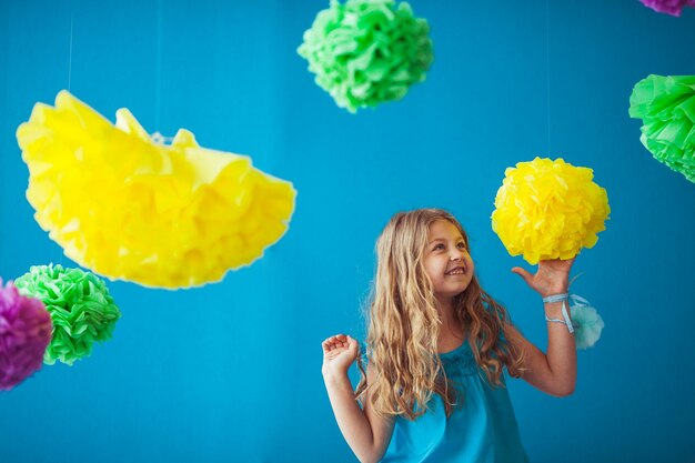 Piccola ragazza carina che gioca con fiori colorati in casa