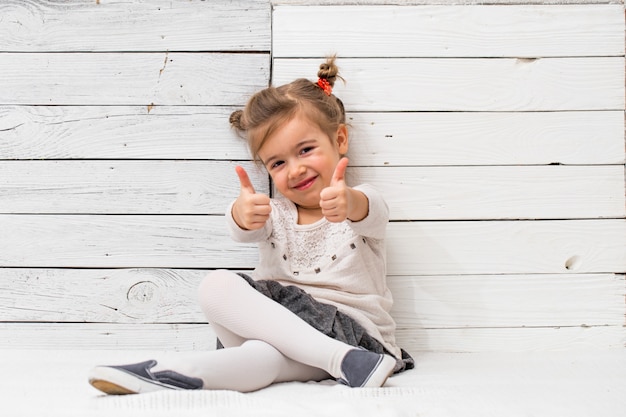 Free photo little cute girl school girl sitting on white wood