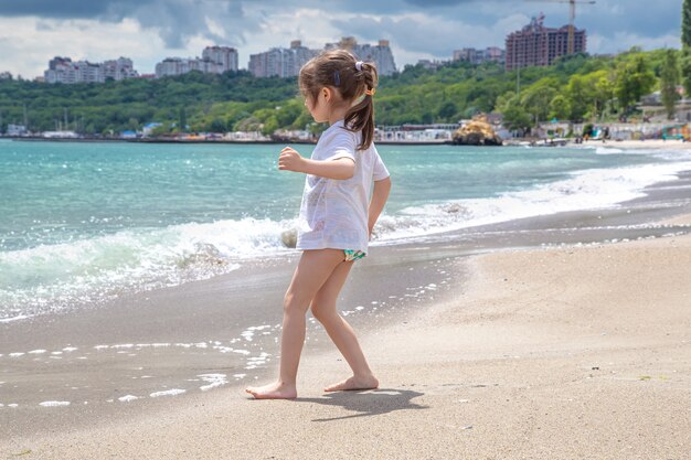 Little cute girl on a sunny day on the beach by the sea.