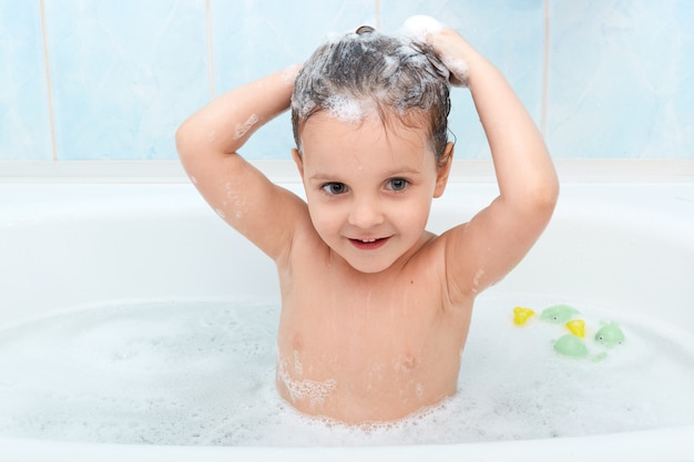 Bambina carina fare il bagno, lavarsi i capelli con lo shampoo da sola