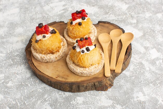 Free photo little delicious cakes with fruits on brown wooden desk