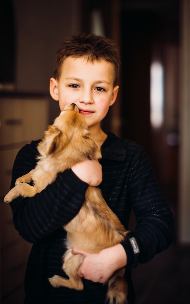 彼は腕の上にそれを保持している間、小さな犬は男の子の顔を舐める
