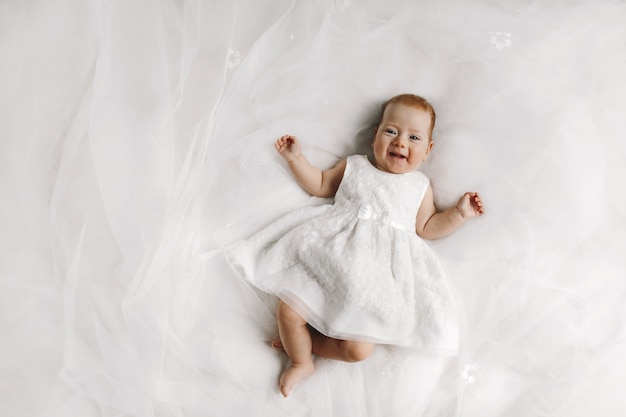 Little female baby lying on the bed and smiling