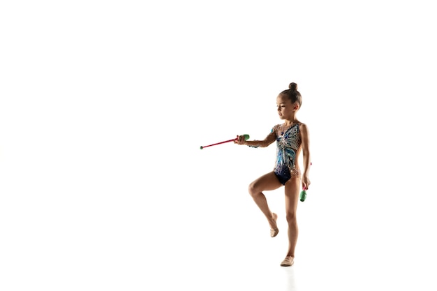 Little flexible girl isolated on white. Little female model as a rhythmic gymnastics artist in bright leotard.