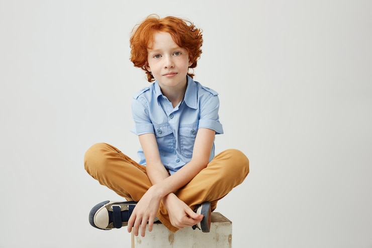 Free Photo little funny boy with orange hair and freckles sitting on wooden box