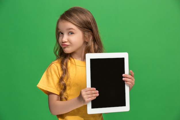 Little funny girl with tablet on green studio