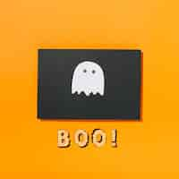 Free photo little ghost on piece of black paper with boo! inscription