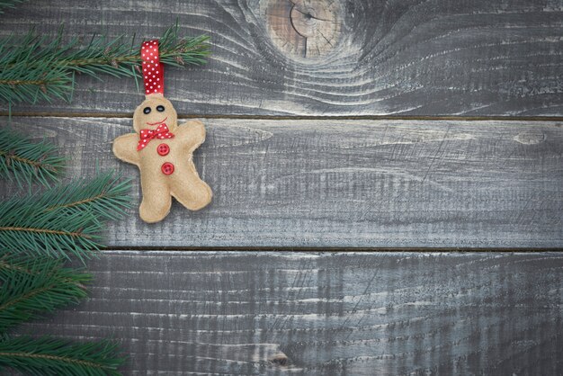 Little gingerbread man hanging on branch of pine tree