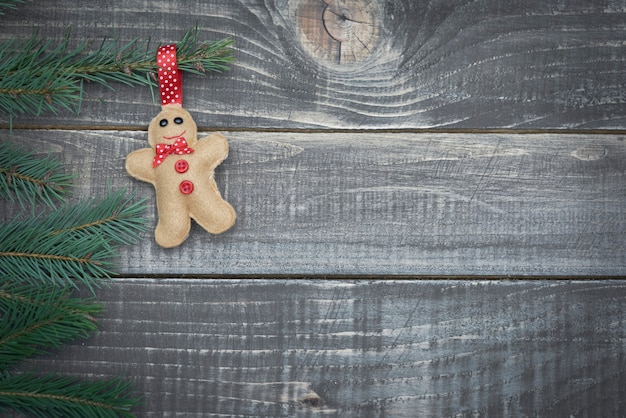 Little gingerbread man hanging on branch of pine tree