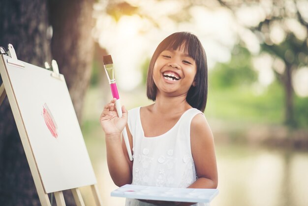 Little girl artist painting picture in the park