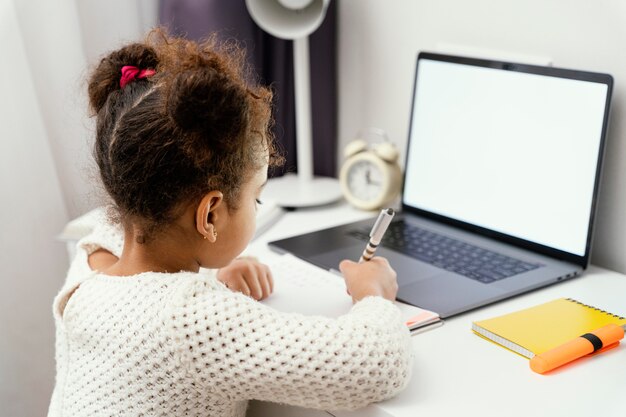 Маленькая девочка, посещающая онлайн-школу дома, используя ноутбук